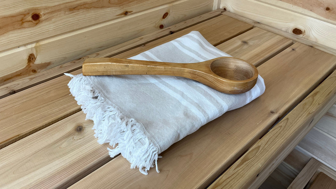 a wood sauna bench with a white sauna towel and wooden ladle