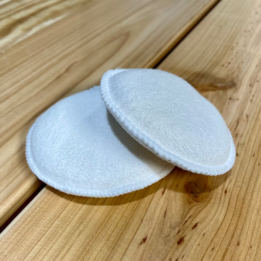 Two white fabric pads on a wooden surface